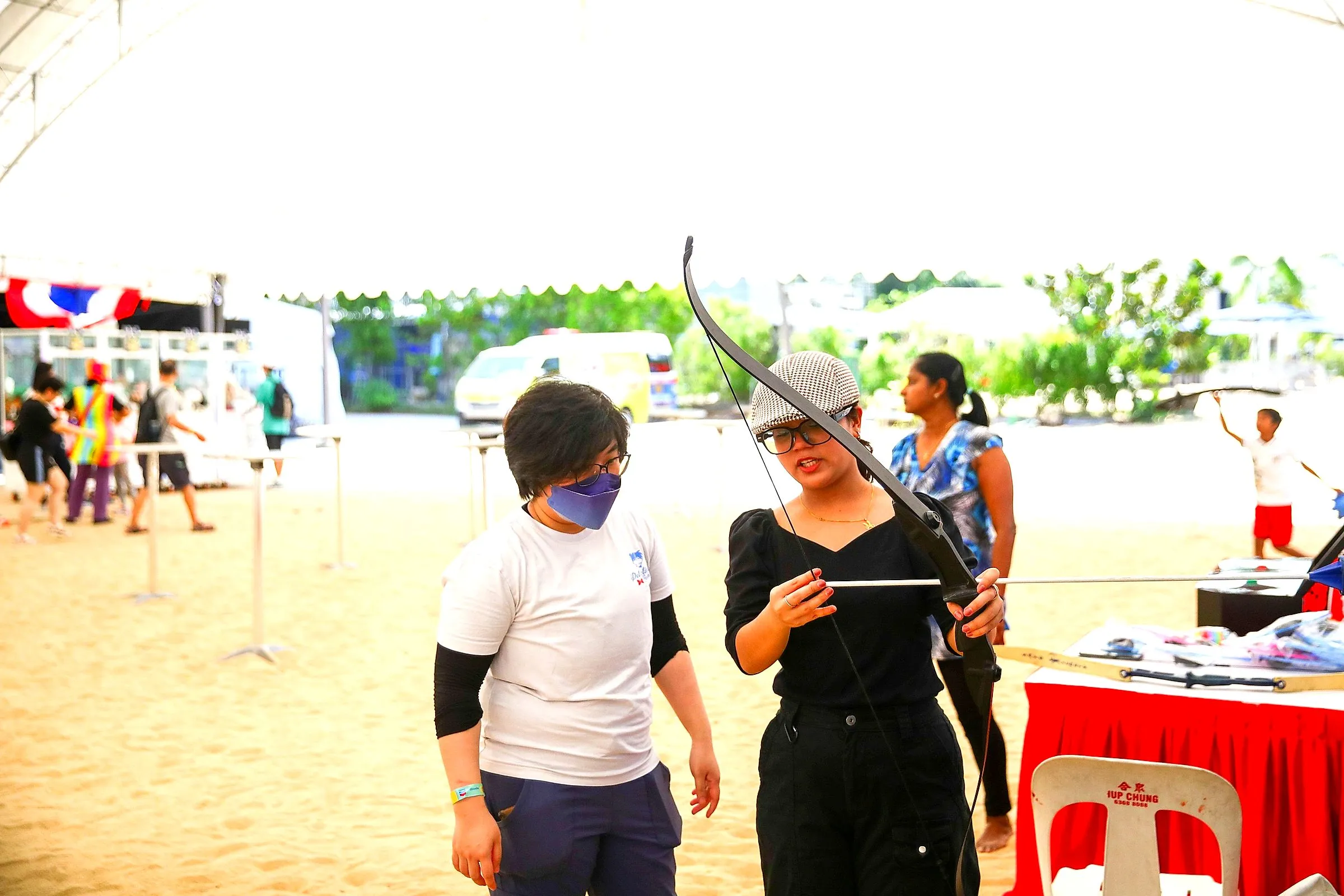Guests trying archery on a sandy beach