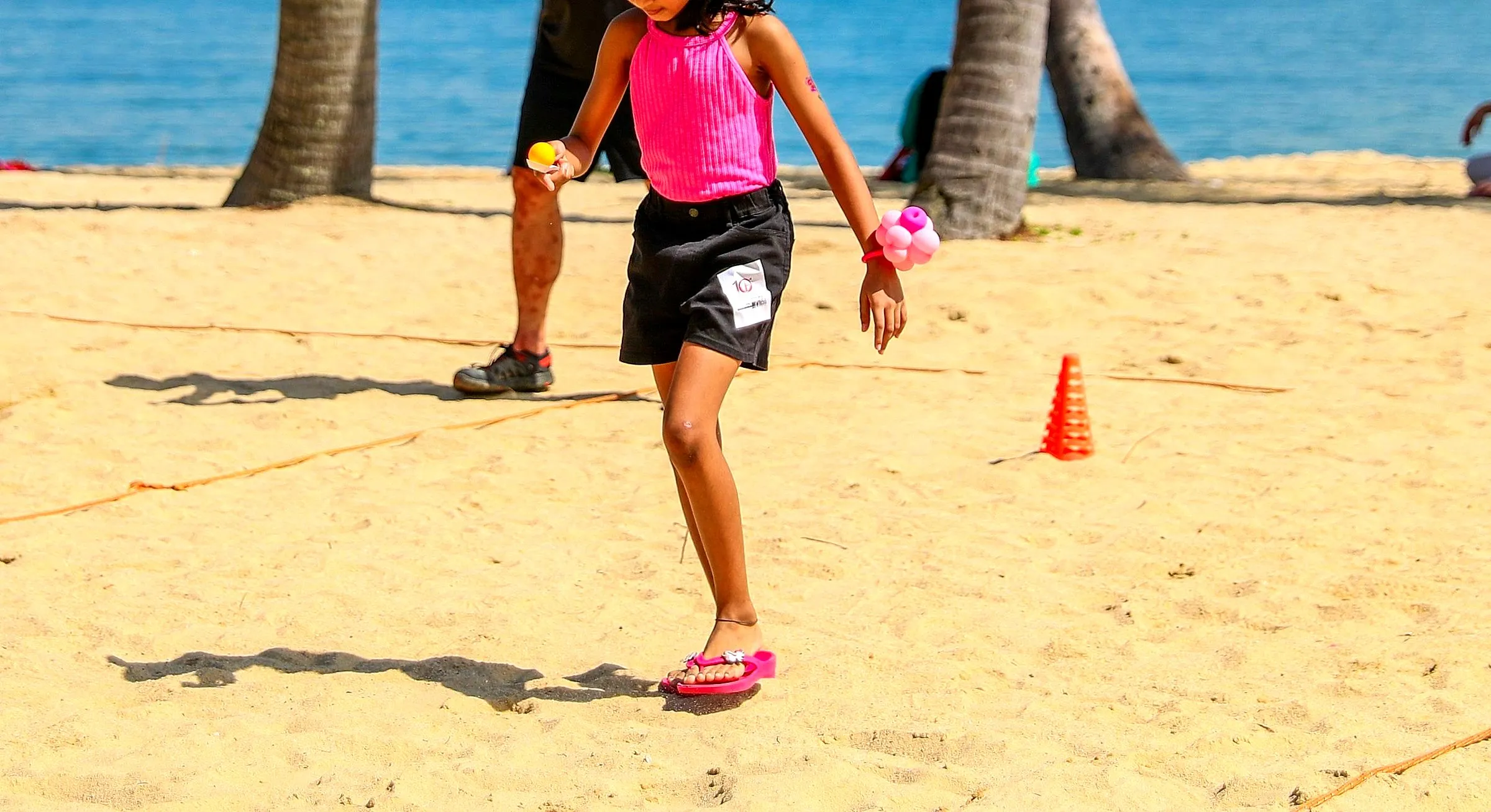 Child running through a beach relay course marked with cones