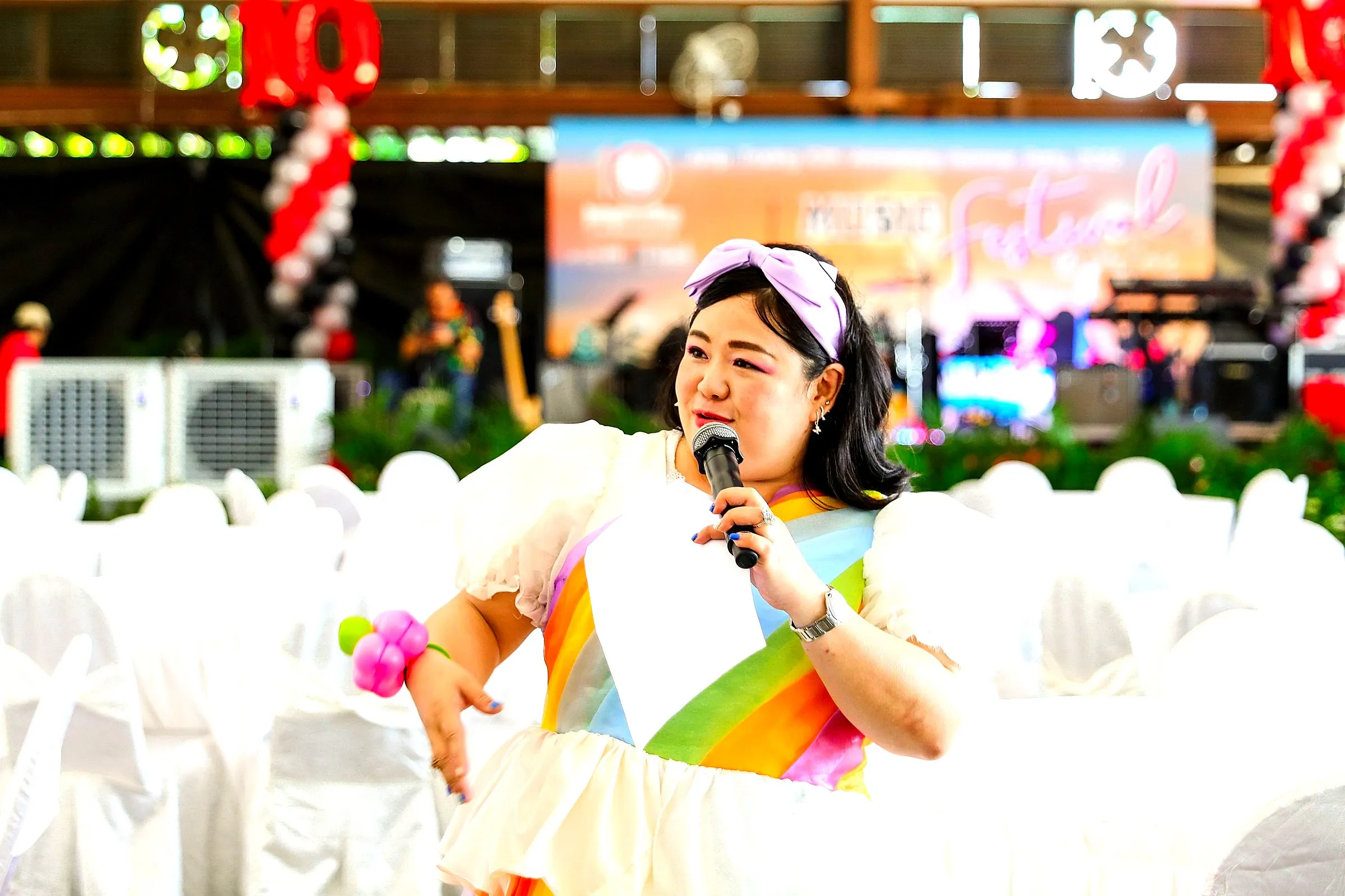 Host in a rainbow dress working the crowd at a family day