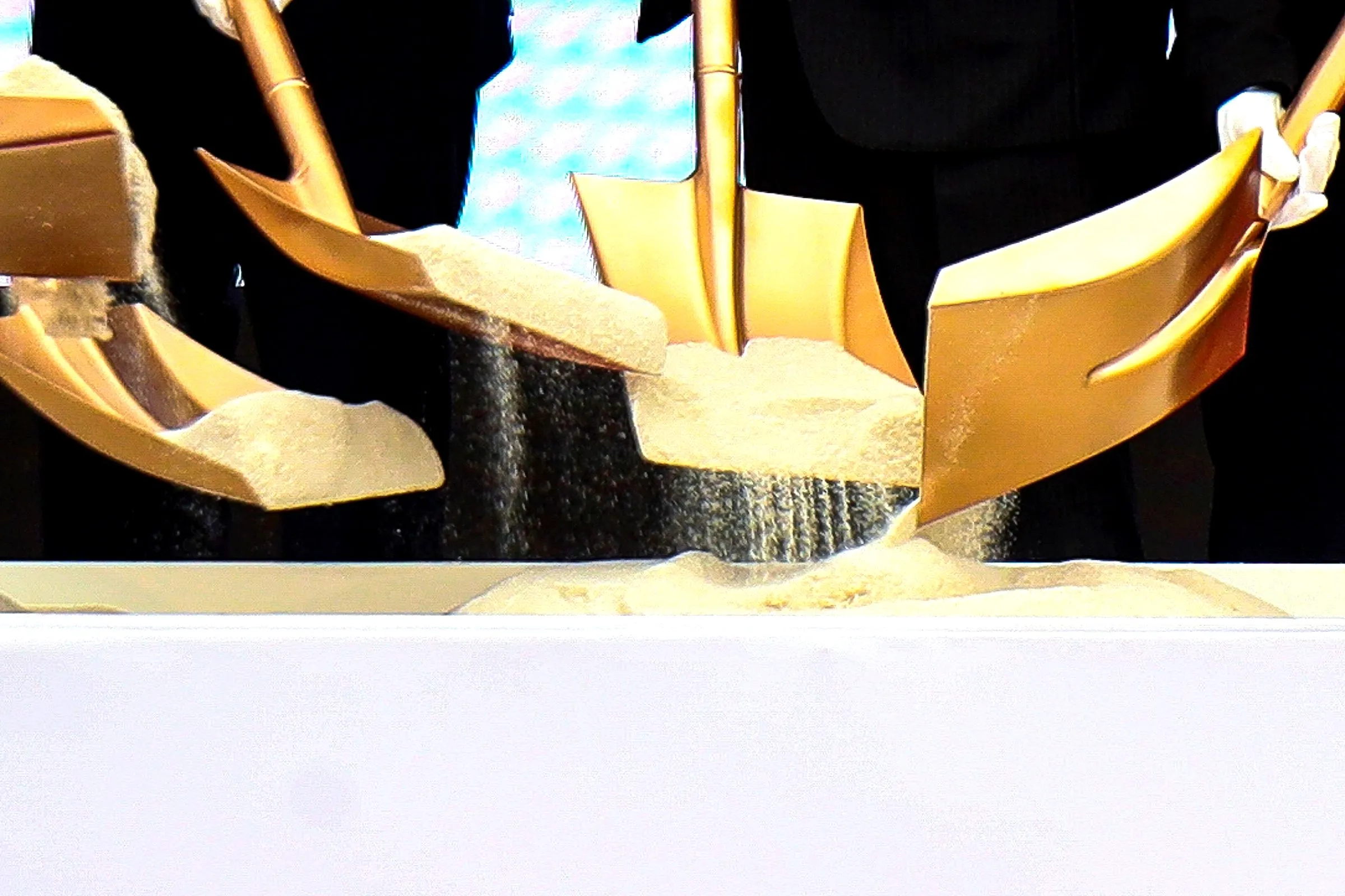 Gold shovels turning sand at a ground-breaking ceremony