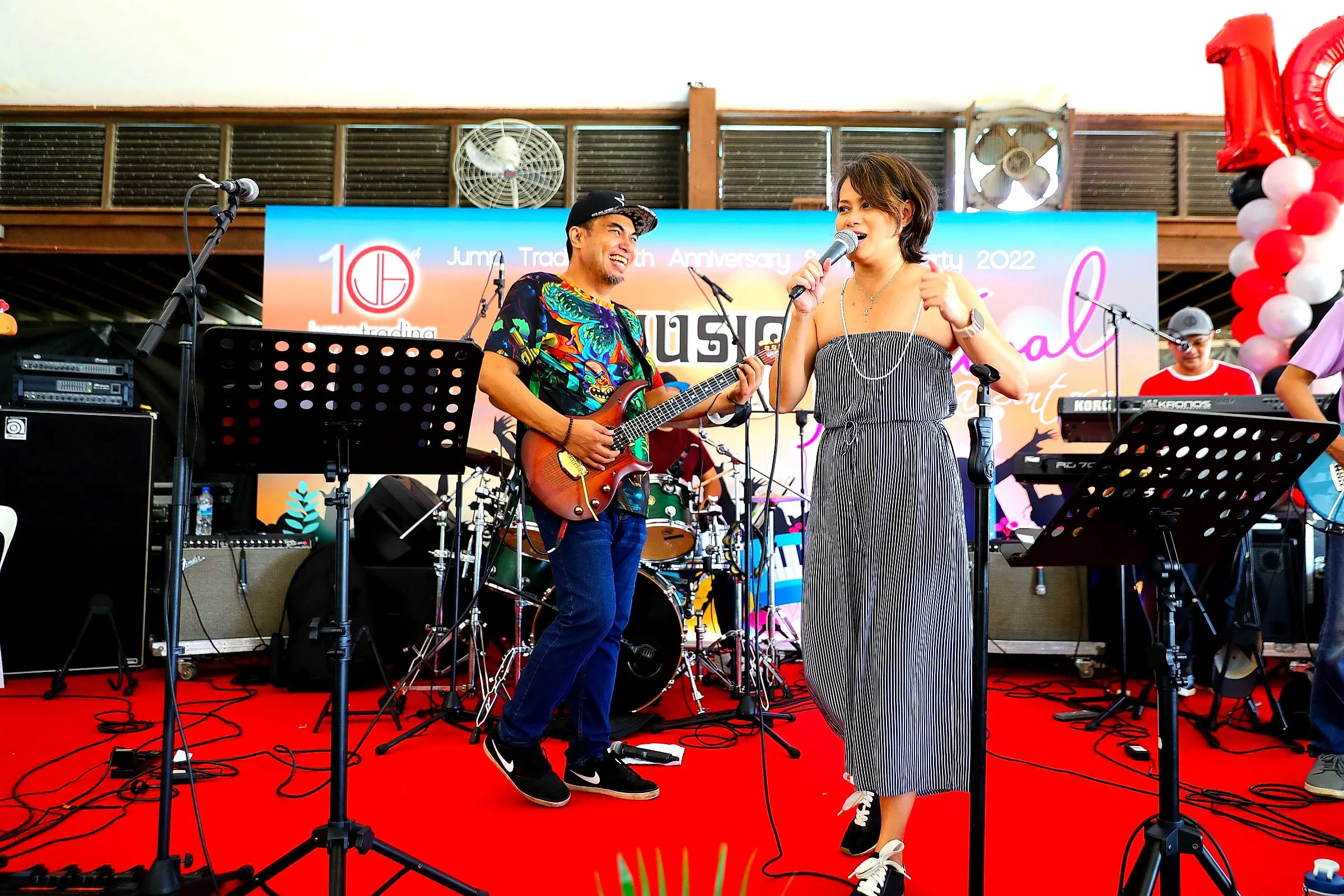 Live band with a singer and guitarist performing on a red-carpeted stage