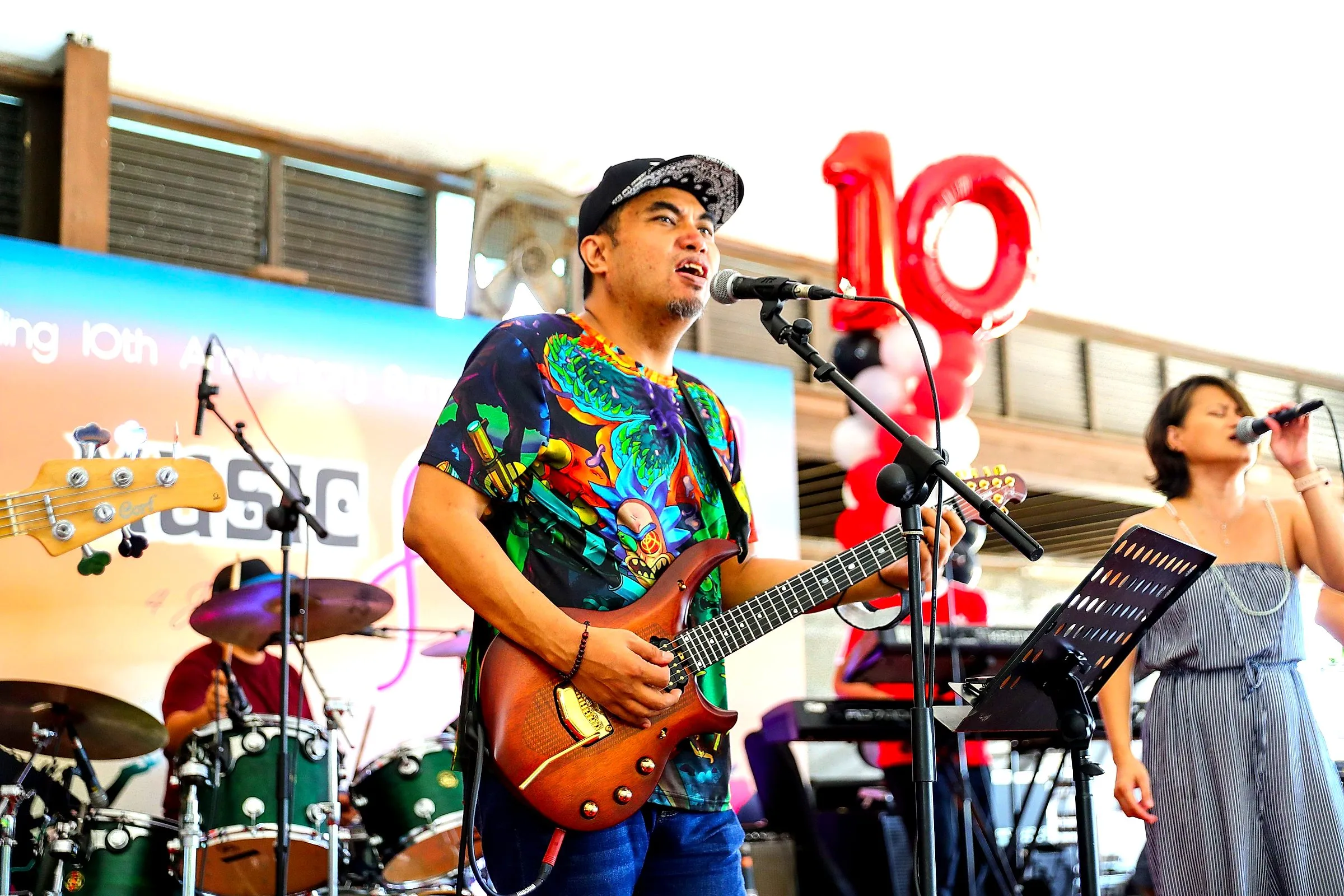 Guitarist and singer performing with a live band beneath balloon arches
