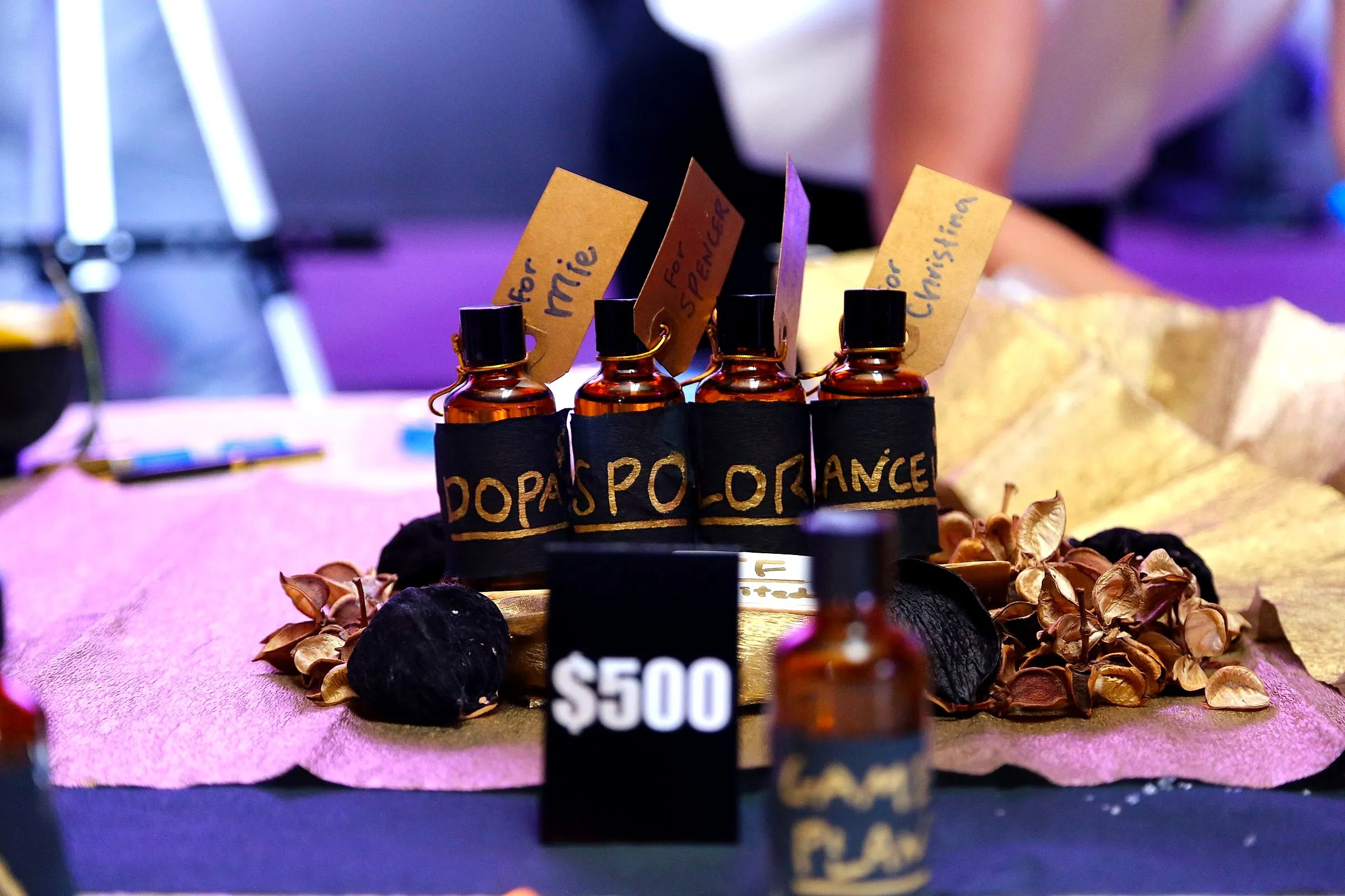 Hand-labelled perfume bottles with name tags on a styled table at a scent-blending station